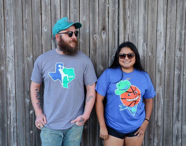 Photo of a man wearing the Bullzerk GOAT tshirt standing next to a woman wearing the Bullzerk Basketball Cowboy tshirt. 