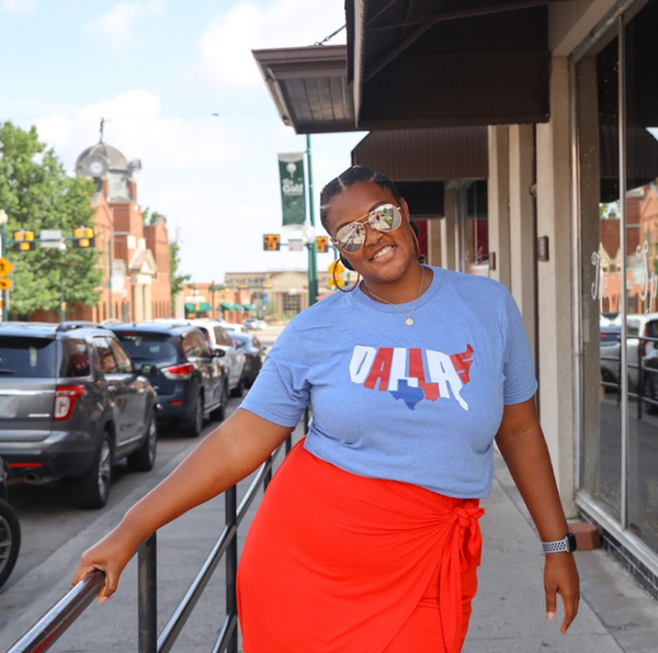 Woman standing outside wearing sunglasses and a Bullzerk Patriotic Dallas tshirt. 