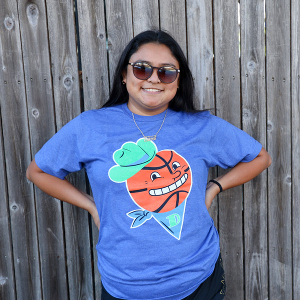 Photo of a woman wearing the Bullzerk Basketball Cowboy tshirt standing in front of a wooden fence smiling.