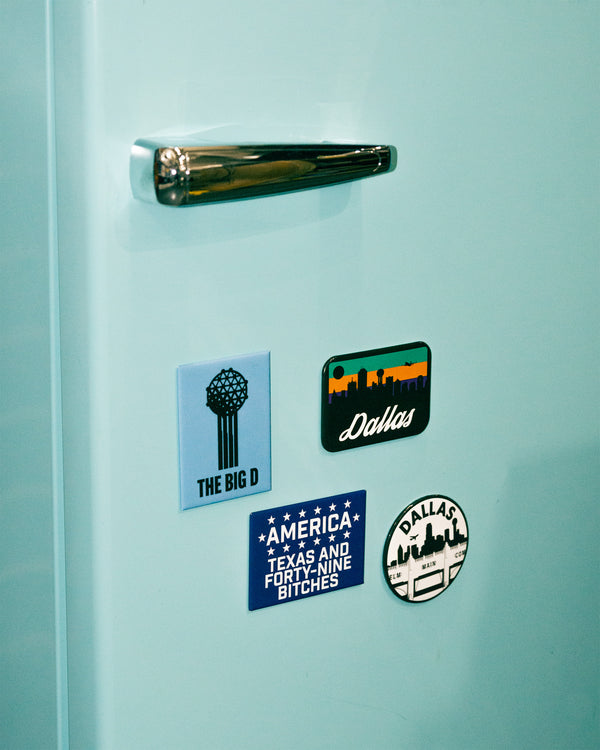 Set of four Dallas-themed stickers on a light blue refrigerator.