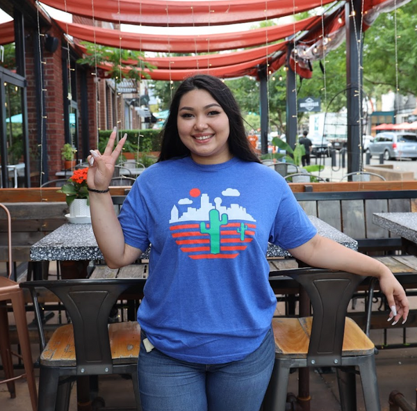 Photo of a woman wearing the Bullzerk Cactus tshirt, smiling and making a peace sign with her hand. 