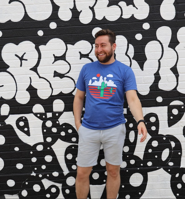 Man wearing a Bullzerk Cactus t-shirt standing in front of a black and white abstract mural.