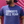 Close up photo of a man wearing the Bullzerk Cowboys Hell Yeah tshirt in front of a pink wall. 