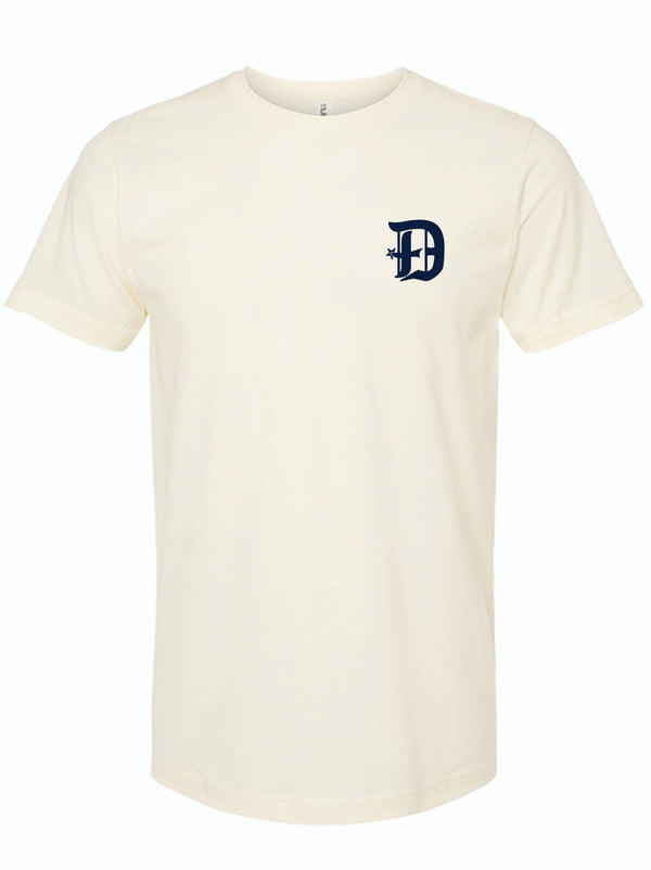 Cream colored tshirt with a D spur logo on the left chest area in dark navy ink. 