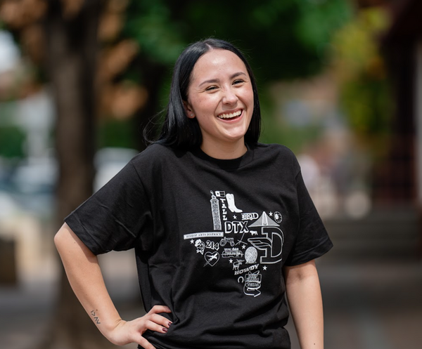 Woman standing outside and laughing, wearing a Bullzerk Icons of Dallas tshirt.