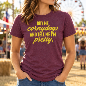 Woman wearing a maroon Buy Me Cornydogs and Tell Me I'm Pretty T-shirt at a fairground