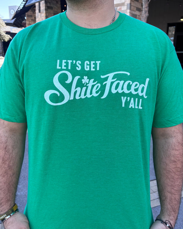 Person wearing a green tshirt with graphic of text reading " Let's get shite faced y'all" in white letters. 