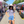 Woman at an outdoor pop-up market, wearing sunglasses, a hat and a Bullzerk  Oak Cliff that's my Hood tshirt. 
