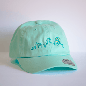 Embroidered Skyline Plant Hat - Lagoon Blue featuring a vibrant skyline design perfect for any Texas themed gift lover. This 100% cotton, unstructured hat makes a great Dallas souvenir and is an ideal choice among Texan gifts or Texas Made Gifts.
