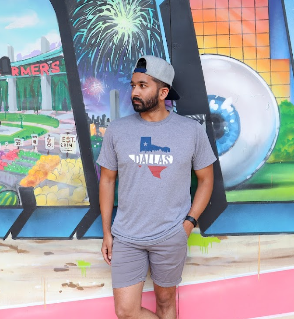 Photo of a man wearing the Bullzerk Dallas Skyline Silhouette tshirt standing in front of an art mural. 