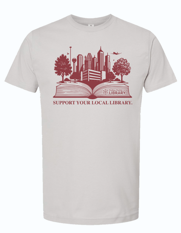 Light gray unisex t-shirt featuring the design 'Support Your Local Library' with a skyline illustration representing Dallas. Perfect for showing love for literature and local community, this shirt is a great Texas themed gift, Texas Made Gifts, and a souvenir from Texas for book lovers or as a Dallas souvenir. Ideal for those looking for unique Texan gifts.