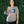 Woman standing in front of greenery, wearing a Bullzerk Texans Love Baseball tshirt and holding a canned drink in a koozie. 