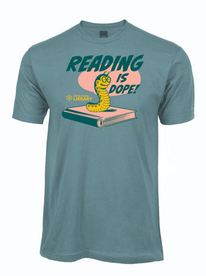 The 'Reading Is Dope' tee features a playful caterpillar on a book, perfect for book lovers. Show your support for the Dallas Public Library with this Texas themed gift. Ideal as a Texas Made gift, this t-shirt makes a great souvenir from Texas, adding charm to any Texan's wardrobe while promoting literacy.