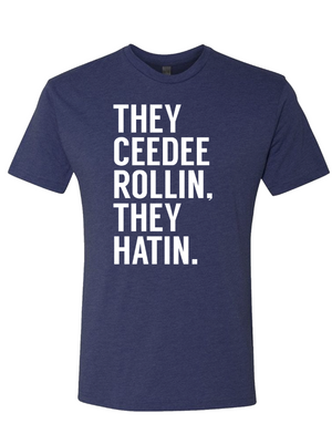 A navy blue unisex fine jersey tee featuring the phrase 'They Ceedee rollin, they hatin.' Perfect as a Texas themed gift or a souvenir from Texas, this shirt represents the vibrant culture of Dallas and makes a great addition to any Texan gifts collection.